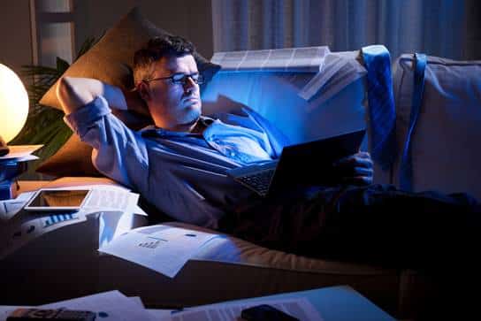 Man laying in bed looking at computer
