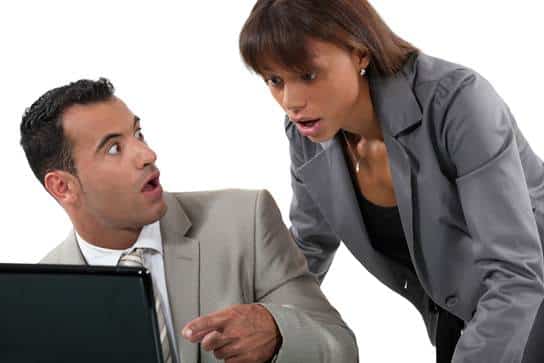 Two coworkers looking at a computer, shocked at the news