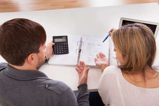 Couple sitting at desk looking at bills